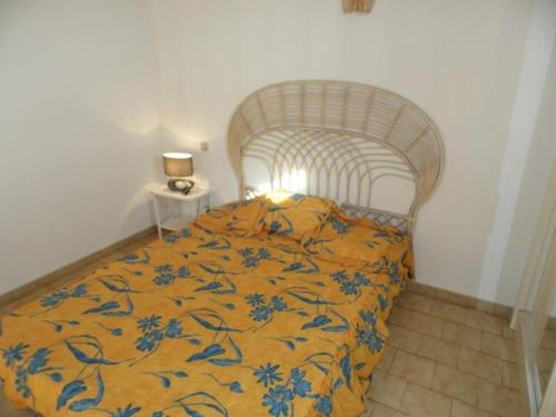 - une chambre avec un lit doté d'une couverture jaune et bleue dans l'établissement Appartement 2 pièces avec mezzanine et parking privé, animaux admis - FR-1-326-405, à Marseillan