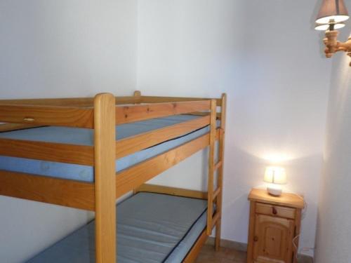 Ce lit superposé en bois se trouve dans un dortoir doté d'une lampe. dans l'établissement Appartement 2 pièces 6 couchages, terrasse, parking privé, sud - FR-1-326-458, à Marseillan