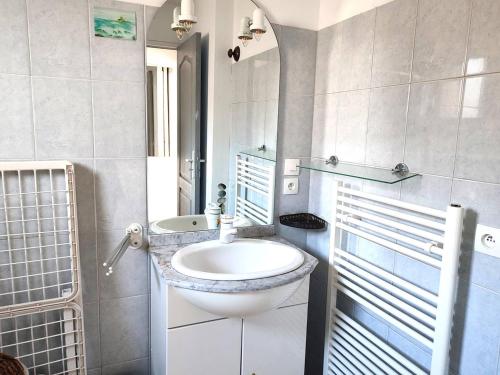 une salle de bain blanche avec un lavabo et un miroir dans l'établissement Maison à 210m de la plage avec jardin clos, terrasse et parking privé sur l'Île Grande - FR-1-368-214, à Pleumeur-Bodou