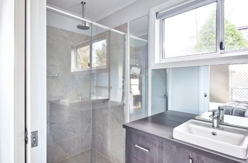 ein Bad mit einer Dusche, einem Waschbecken und einem Spiegel in der Unterkunft NRMA Jindabyne Holiday Park in Jindabyne