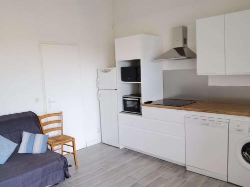 une petite cuisine avec un canapé et une cuisinière four supérieur dans l'établissement Maison spacieuse climatisée, 3 chambres, terrasse, cuisine neuve, accès direct à la mer, à Marseillan - FR-1-326-719, à Marseillan