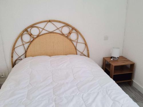 une chambre avec un lit blanc avec une tête de lit en bois dans l'établissement Maison spacieuse climatisée, 3 chambres, terrasse, cuisine neuve, accès direct à la mer, à Marseillan - FR-1-326-719, à Marseillan