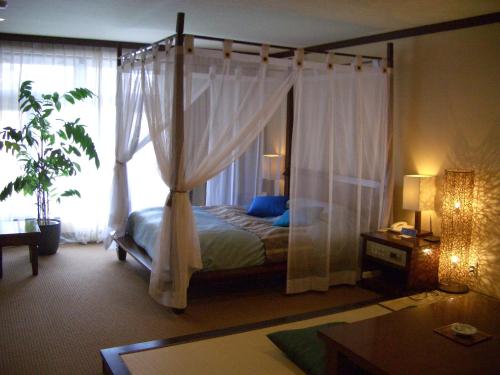 a bedroom with a canopy bed and a window at Wellness Forest Nasu in Nasu