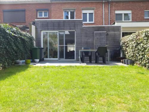 een patio met een tafel en stoelen in een tuin bij Ruime woning met 4 slaapkamers nabij Antwerpen en haven in Brasschaat