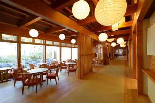 un restaurante con mesas, sillas y ventanas grandes en Yukemuri no Yado Inazumi Onsen, en Yuzawa