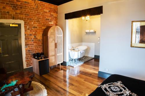 a bathroom with a brick wall and a bath tub at Hotel Australasia in Eden