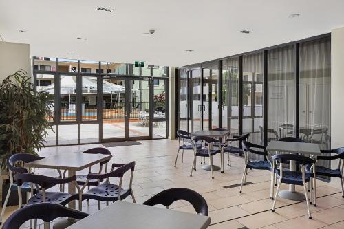 une cafétéria avec des tables, des chaises et des fenêtres dans l'établissement Aqualine Apartments On The Broadwater, à Gold Coast