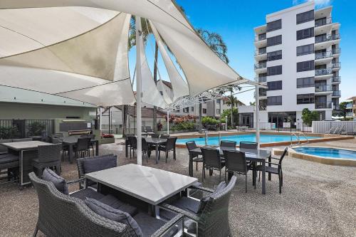 a patio with tables and chairs and an umbrella at Aqualine Apartments On The Broadwater in Gold Coast