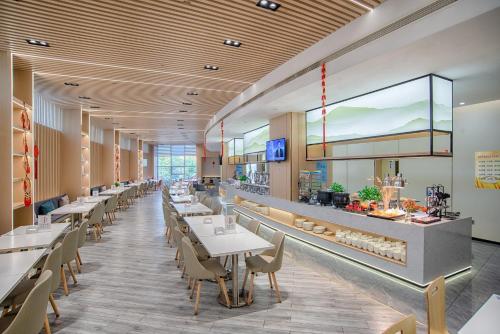 a restaurant with white tables and chairs and a counter at Holiday Inn Express Taian City Center by IHG in Tai'an