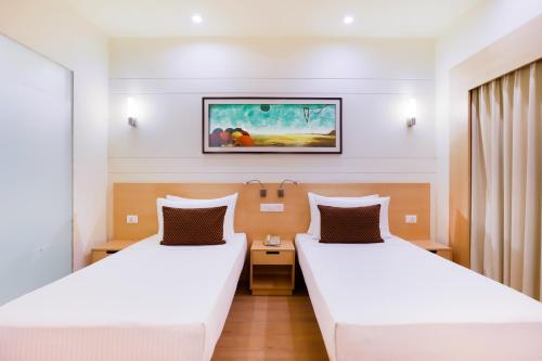 um quarto de hotel com duas camas e uma foto na parede em Lemon Tree Hotel Whitefield, Bengaluru em Bangalore