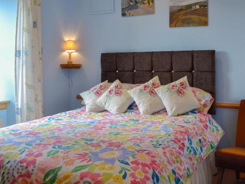 a bed with a colorful comforter with four pillows at Laurel Bank in Alyth