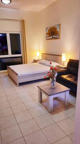 Un dormitorio con una cama y una mesa con flores. en Stufio flat DG085, Close to The Gardens Metro 6 min walkable, en Dubái