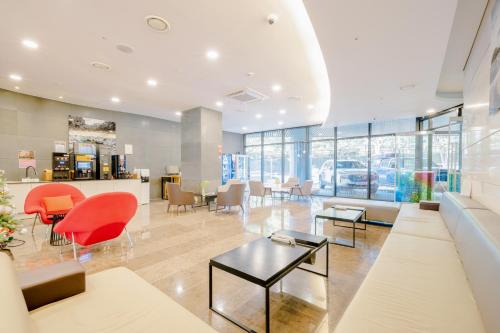 a lobby of a car dealership with red chairs and tables at Hotel bridge Seogwipo in Seogwipo