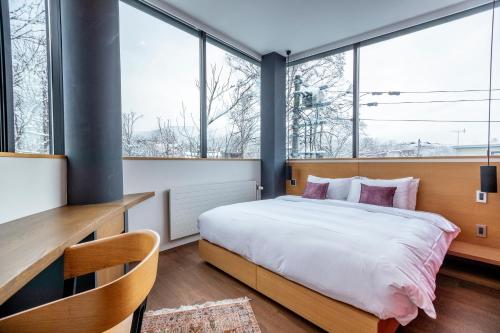 a bedroom with a large bed and large windows at Yasuragi in Niseko