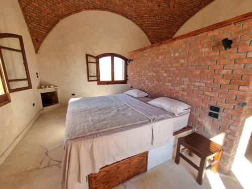 a bedroom with a large bed in a brick wall at A Home with a Dome in ‘Izbat Ţanāţī