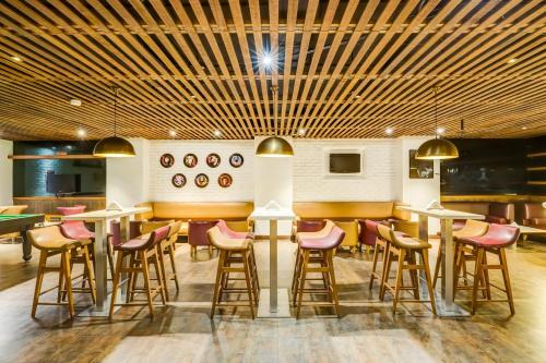 a restaurant with a bar with stools and tables at Lemon Tree Hotel Electronics City in Bengaluru