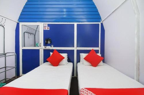 two beds in a room with blue and red pillows at A4 Hostel Colombo Airport - travellers cottage in Katunayake