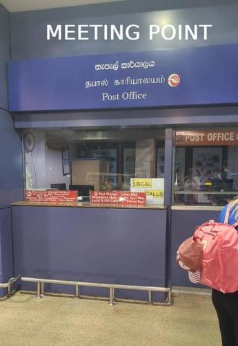 a person with a pink bag standing in front of a meeting point at A4 Hostel Colombo Airport - travellers cottage in Katunayake