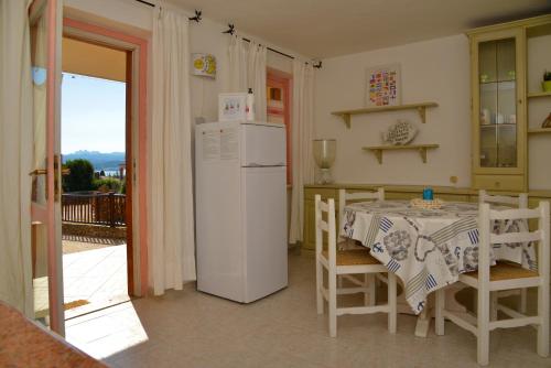 uma cozinha com um frigorífico branco e uma mesa com cadeiras em Casa UGB em Cannigione