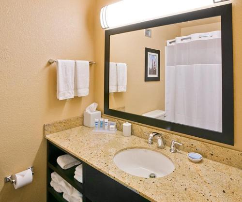 a bathroom with a sink and a large mirror at Wyndham Garden Oklahoma City Resort & Conference Hotel Near Airport, Fairgrounds Paycom & I40 in Oklahoma City