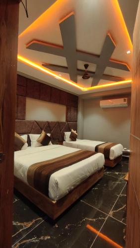 two beds in a room with lights on the ceiling at Hotel Prime Land in Ahmedabad