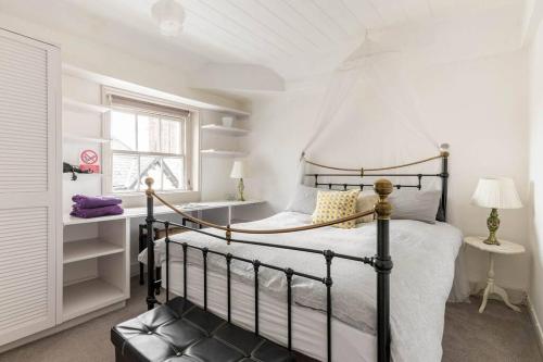 ein Schlafzimmer mit einem schwarzen Bett in einem weißen Zimmer in der Unterkunft Medieval roots and Harry Potter TownHouse - Hiking near Ludlow in Leominster