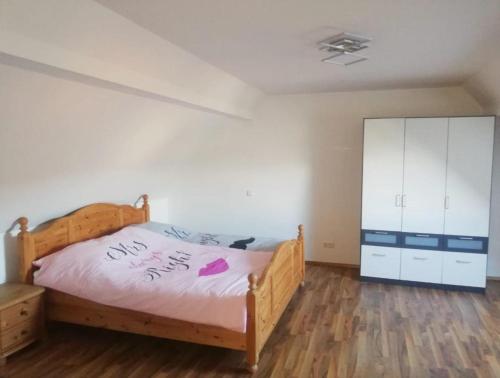 1 dormitorio con cama de madera y armario blanco en Biohof Laibacher, en Stubenberg
