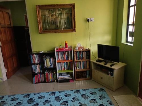a living room with a tv and book shelves filled with dvds at HOMESTAY JANNATI TAMBUN in Tambun