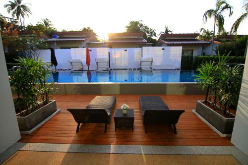 a swimming pool with chairs and a table in front of it at The Fusion Resort Hotel in Chalong