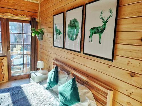 a bedroom with a bed and some pictures on the wall at Pokoje i Domki Na Szlaku in Polanica-Zdrój
