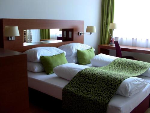 a hotel room with two beds with green pillows at Golf & Wellness Apartment 34. in Bad Waltersdorf