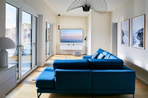 a living room with a blue couch and large windows at Dahmeloft in Dahme