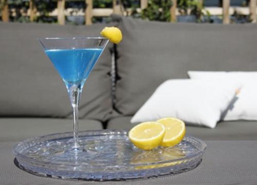 a glass with a blue drink and two lemons on a table at Blue Cosmo Apartment in Taʼ Xbiex
