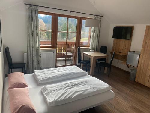 Schlafzimmer mit einem Bett, einem Tisch und einem Fenster in der Unterkunft Wurznwirt in Schneizlreuth