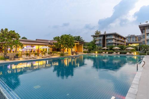 une grande piscine avec des chaises et des condos dans l'établissement Sand Dunes Chaolao Beach Resort, à Chao Lao Beach
