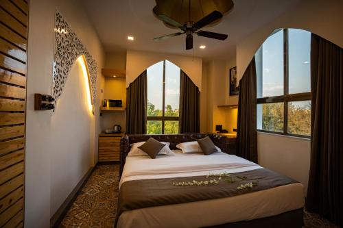 a bedroom with a large bed with two windows at Ra Residence - Agarwal Group of Hotels in Pune