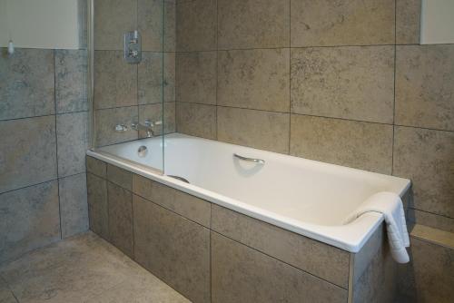 La salle de bains carrelée est pourvue d'une baignoire. dans l'établissement Dukeswood Cottage, Wynyard Hall, 