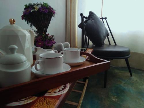 una mesa con tazas y platos con una silla en Barefoot Inn Kandy en Kandy