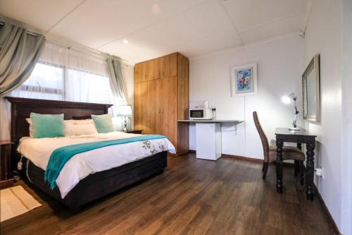 - une chambre avec un lit, un bureau et un four micro-ondes dans l'établissement Casabella Guesthouse, à East London