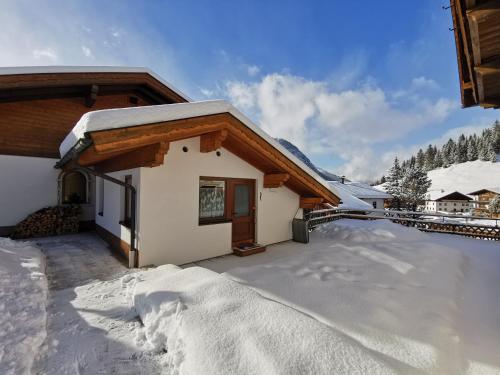 una casa con nieve en el suelo delante de ella en Haus Steinkarblick und Berghäusl, en Berwang