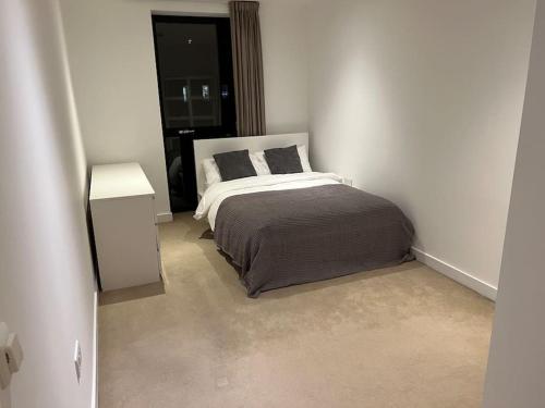 a white bedroom with a bed and a window at Modern 2 bed - Olympic Park Stratford in London