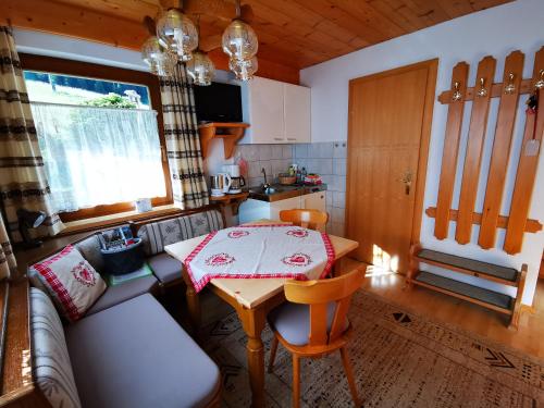 uma sala de estar com uma mesa e um sofá e uma cozinha em Haus Steinkarblick und Berghäusl em Berwang