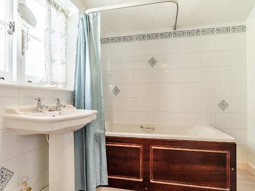a bathroom with a sink and a bath tub at Harvey Cottage in Colyton