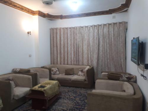 a living room with two couches and a tv at Azzam Guest House 2 families only in Fayoum