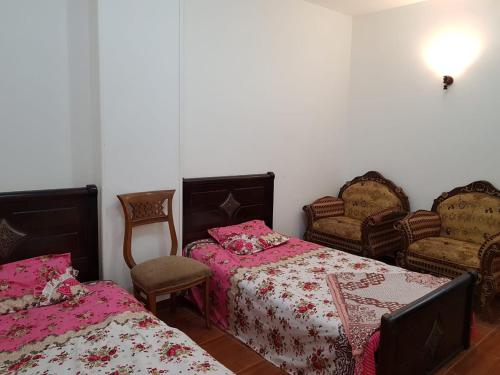 a bedroom with two beds and two chairs at Azzam Guest House 2 families only in Fayoum