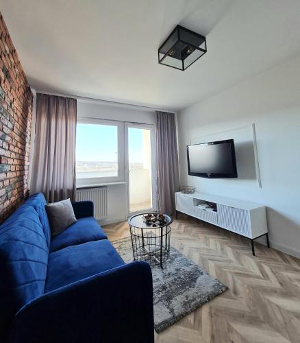 sala de estar con sofá azul y TV en Sun and holidays apartament Władysława IV, en Gdynia
