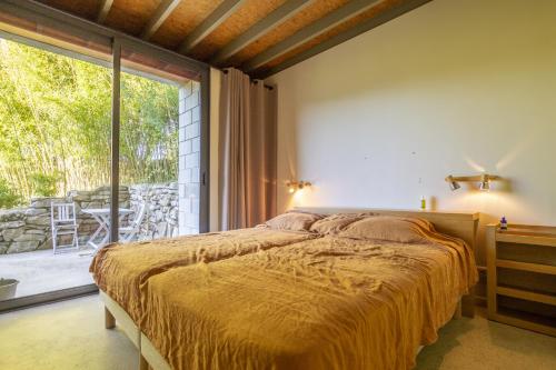 a bedroom with a bed and a large window at La Maison des Chataigniers in Meyrannes