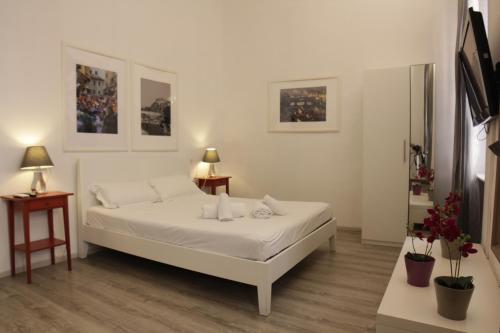 ein weißes Schlafzimmer mit einem weißen Bett und 2 Tischen in der Unterkunft Bronze Horse in Florenz