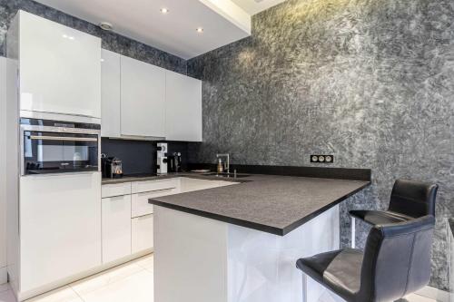 une cuisine avec des armoires blanches et un comptoir noir dans l'établissement Large renovated studio - rue Hoche - Cannes center, à Cannes