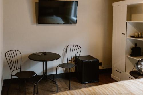 a room with a table and two chairs and a television at Hotel Chapter in s-Gravenzande
